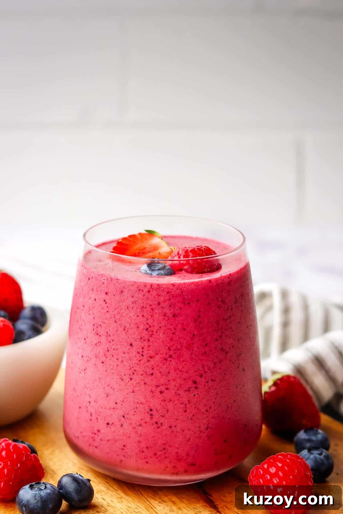 a glass of triple berry smoothie garnished with fresh berries