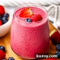 A berry smoothie in a glass garnished with berries.