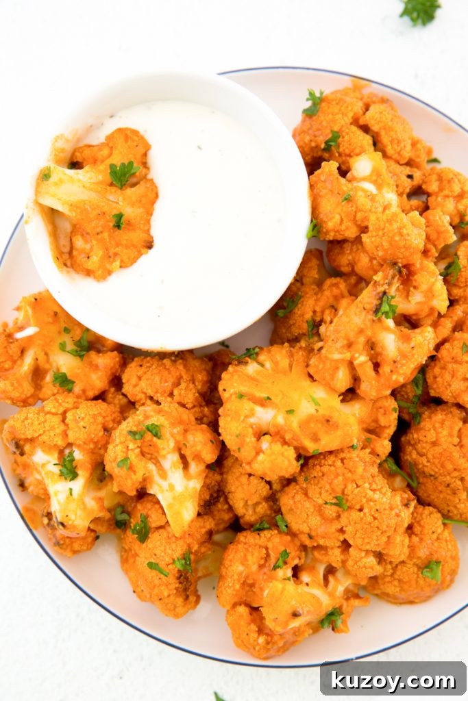 keto buffalo cauliflower on a plate with a side of blue cheese topped with parsley 