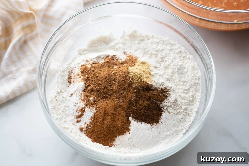 Deliciously tender, easy pumpkin bread is topped with cinnamon and sugar for a family-favorite fall treat you can enjoy on repeat. Dry ingredients for easy pumpkin bread in glass bowl.