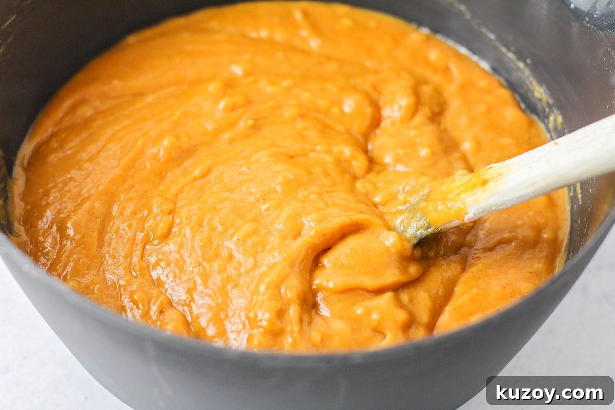 Deliciously tender, easy pumpkin bread is topped with cinnamon and sugar for a family-favorite fall treat you can enjoy on repeat. Pumpkin bread batter mixed in a grey bowl.