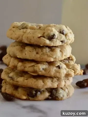 Oatmeal Raisin cookies stacked on a counter with a glass of milk.