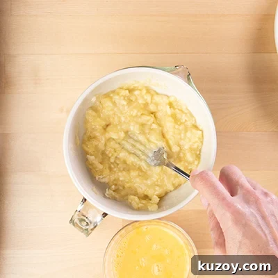 Mashing banana in bowl with fork.
