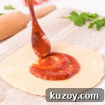 Homemade Pizza Sauce Without Tomato Paste — Fresh & Flavorful 8 Pizza sauce being spread on pizza dough.