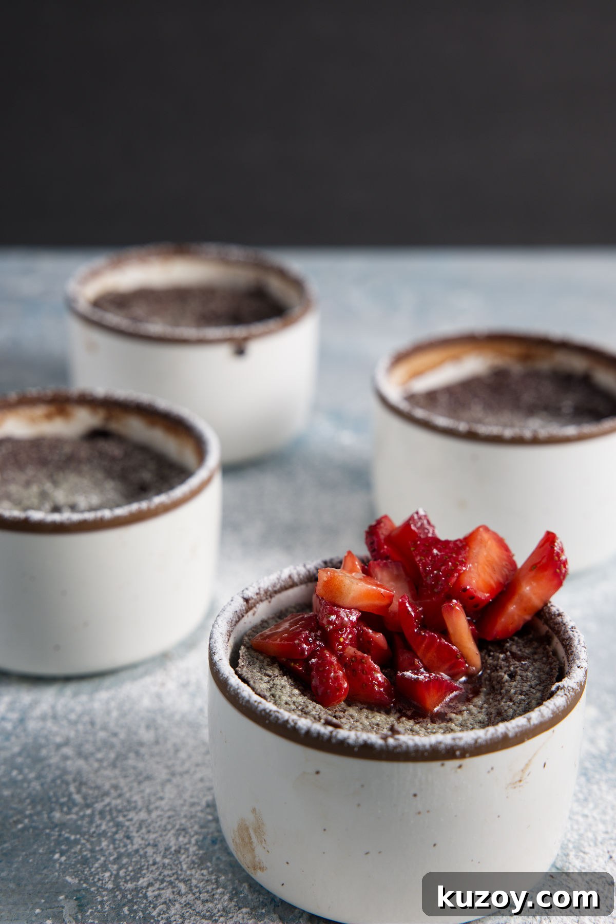 Air Fryer Chocolate Lava Mug Cake Recipe 12 Several air fryer lava cakes in ramekins and topped with chopped strawberries.
