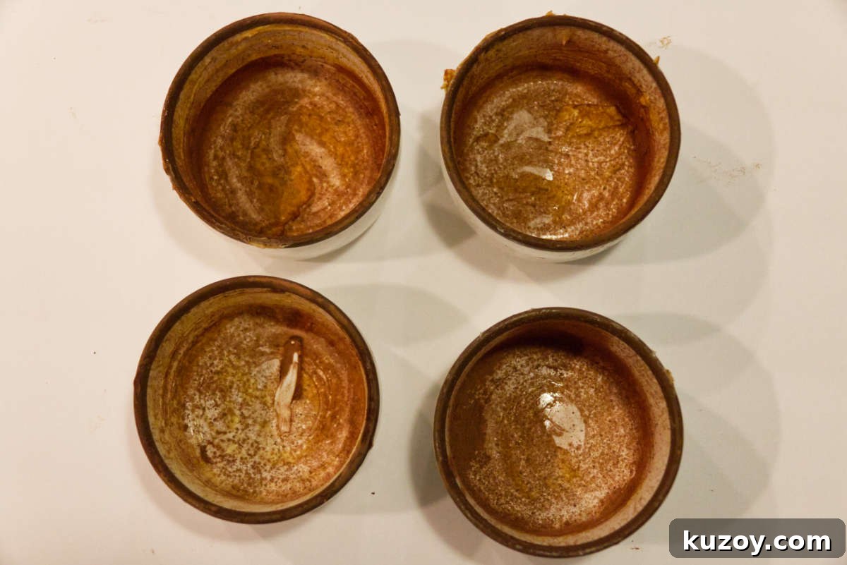 Air Fryer Chocolate Lava Mug Cake Recipe 5 Preparing mugs with butter and cocoa powder.