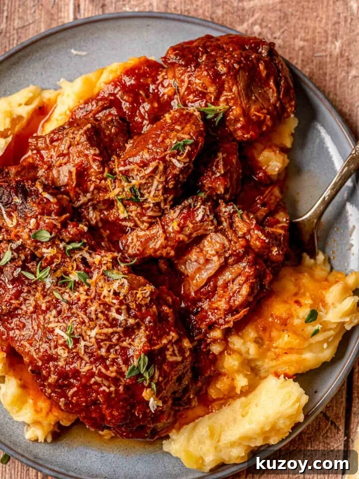 Italian pot roast with mashed potatoes, tomato and red wine gravy, and fresh thyme on a plate.