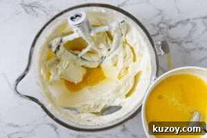 Adding eggs to the cheesecake batter.