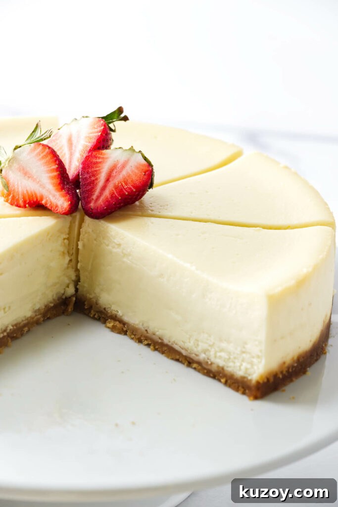 Sliced cheesecake with cookie crust and strawberries on a white plate.