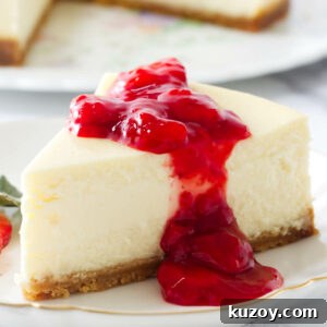 Strawberry sauce on a slice of cheesecake on a plate.