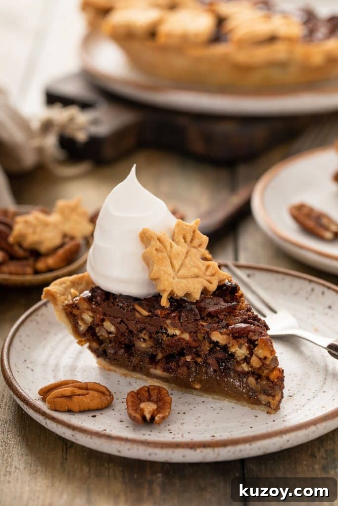 Decadent Chocolate Pecan Pie with Gooey Filling 2 A piece of Chocolate Pecan pie topped with whipped cream and a leaf made of pie crust.