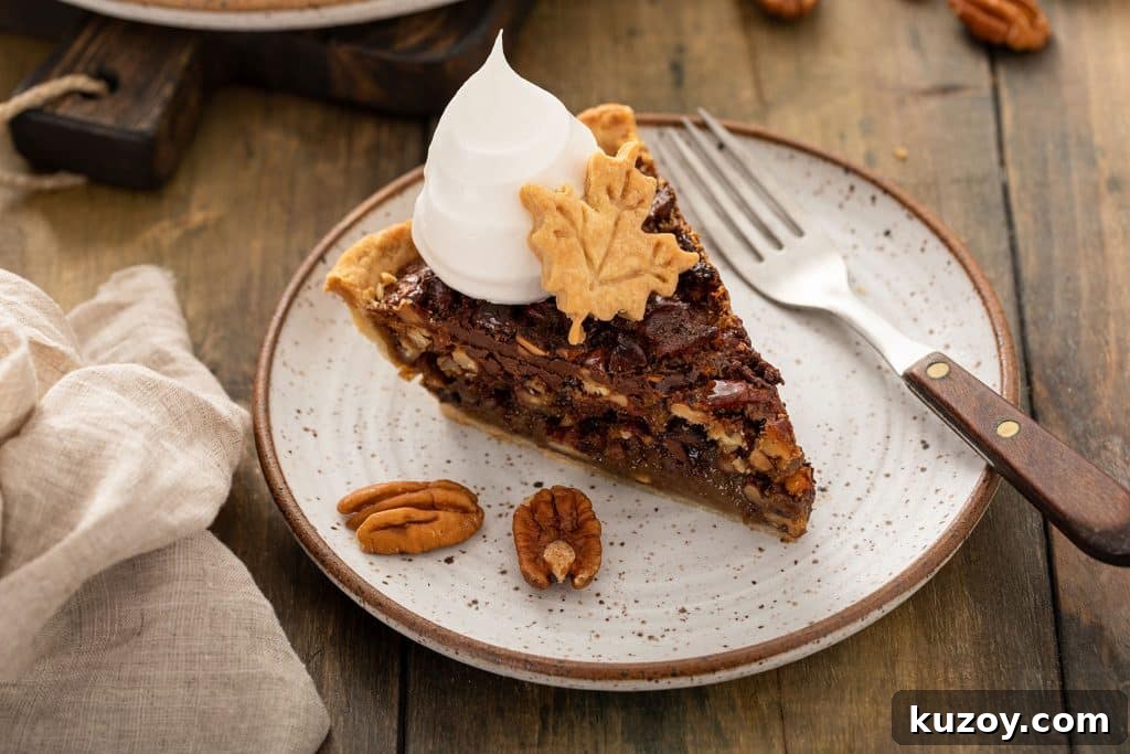 Decadent Chocolate Pecan Pie with Gooey Filling 13 A slice of A piece of Chocolate Pecan pie topped with whipped cream and a leaf made of pie crust.