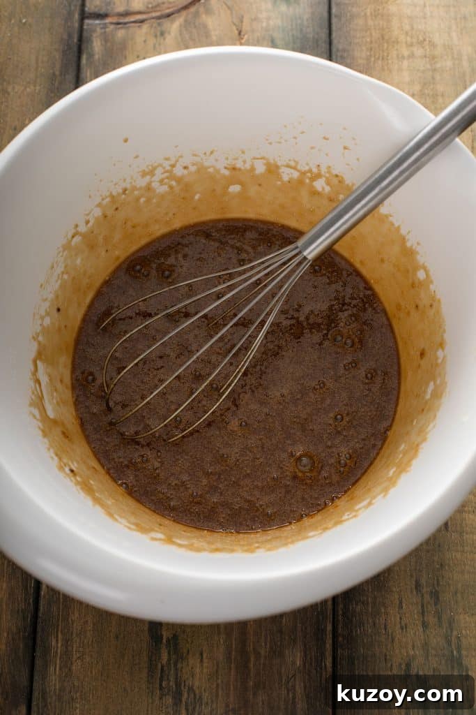 Decadent Chocolate Pecan Pie with Gooey Filling 7 mixed eggs, brown sugar, corn syrup, vanilla extract, melted butter, bourbon and salt in a large mixing bowl with a whisk.