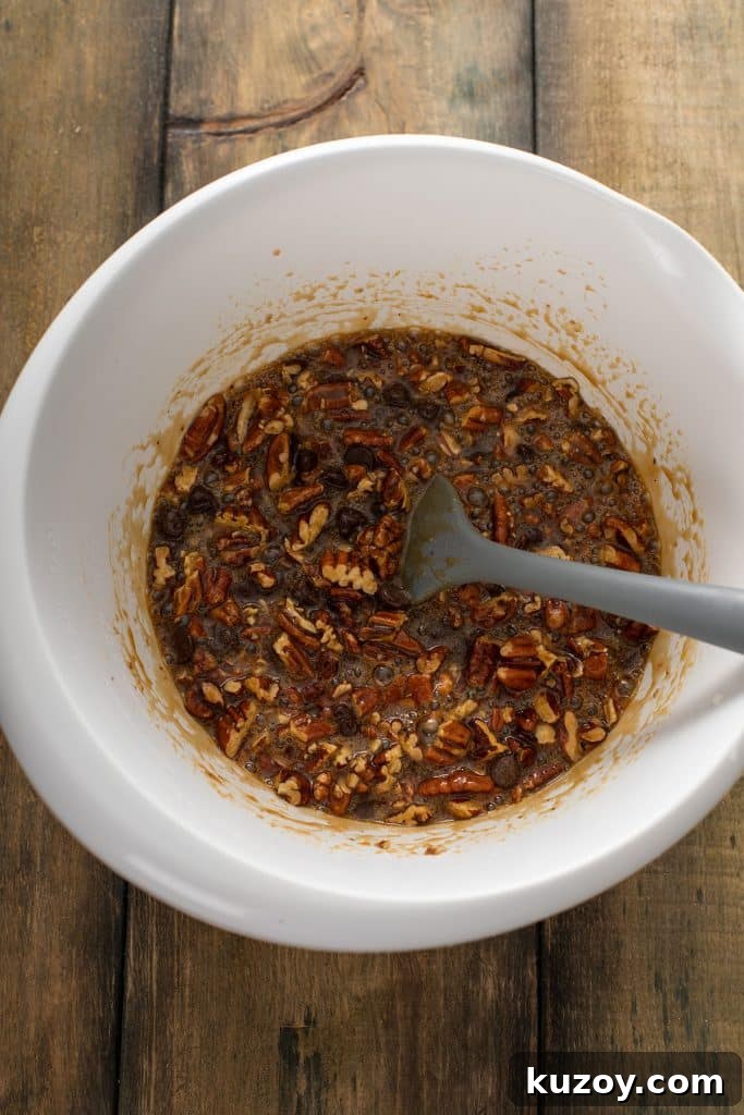 Decadent Chocolate Pecan Pie with Gooey Filling 8 Chocolate pecan pie filling mixed in a large white bowl.