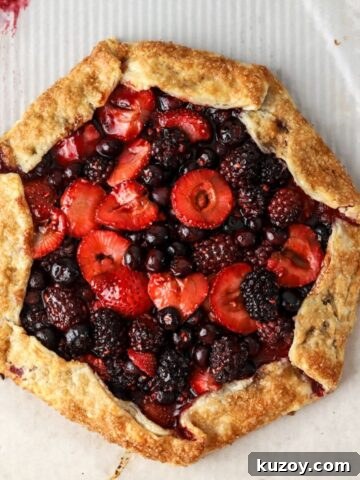 A golden brown galette filled with mixed berries on parchment paper.