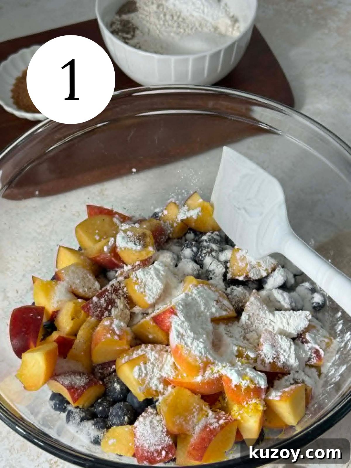 Peach Blueberry Cobbler Recipe: Sweet Summer Fruit Cobbler 4 A glass mixing bowl with cornstarch sprinkled over peaches and blueberries.