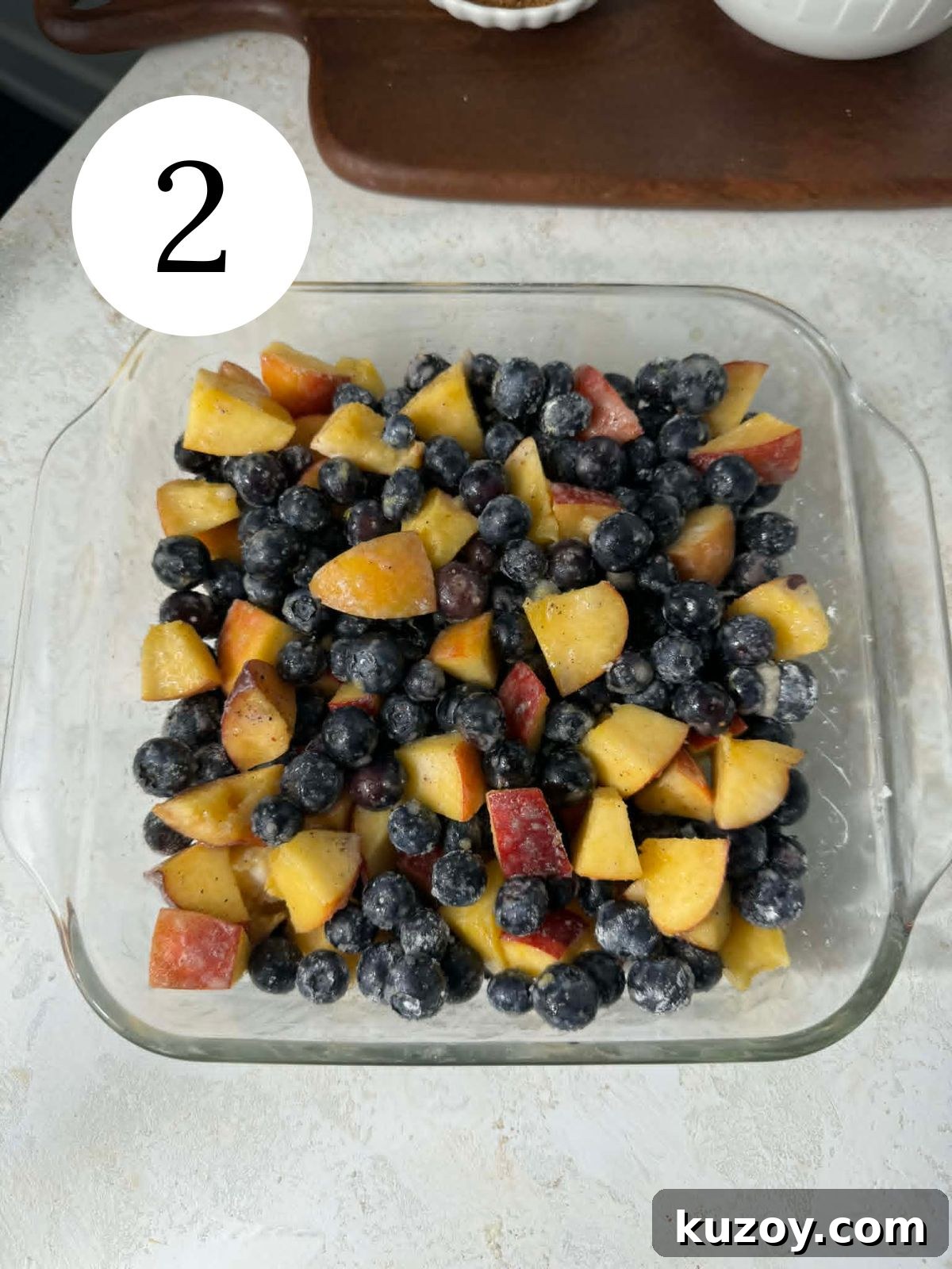 Peach Blueberry Cobbler Recipe: Sweet Summer Fruit Cobbler 5 A glass baking dish filled with blueberries and peaches.