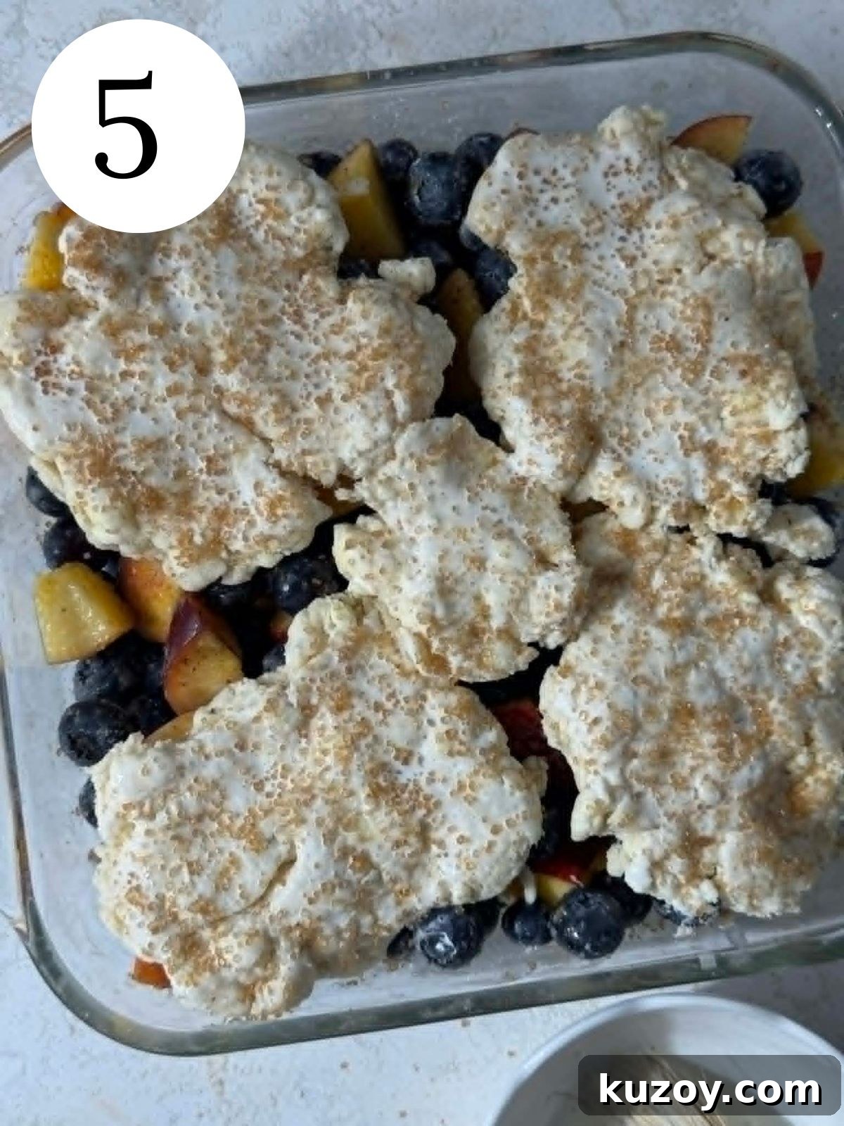 Peach Blueberry Cobbler Recipe: Sweet Summer Fruit Cobbler 8 Cobbler topping spread over fruit, in a glass baking dish.