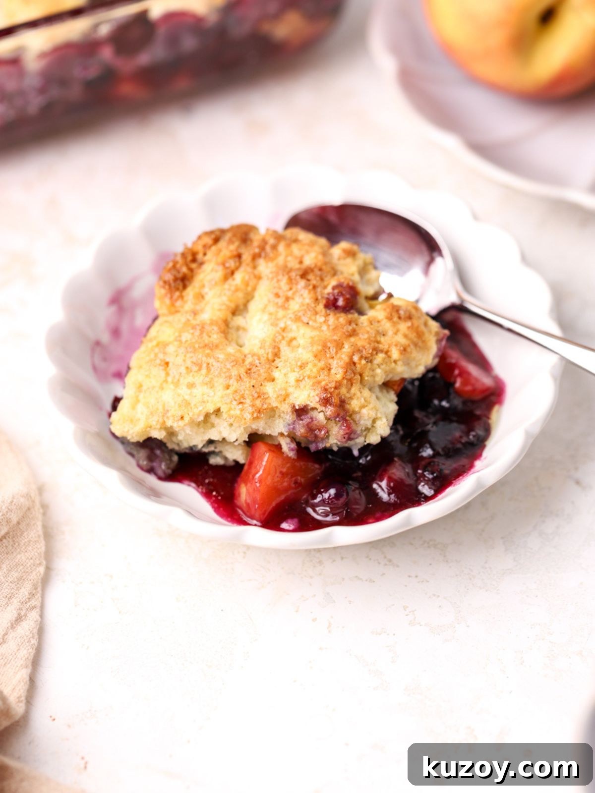 Peach Blueberry Cobbler Recipe: Sweet Summer Fruit Cobbler 10 A bowl with blueberry peach cobbler and a spoon.