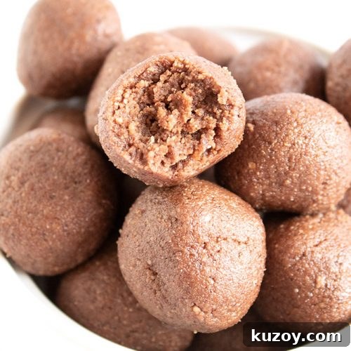closeup of keto chocolate fat bombs in a bowl with piece missing from one