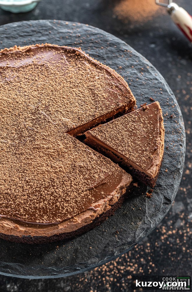 a slice of chocolate cake being cut from the cake placed on a black color cake stand