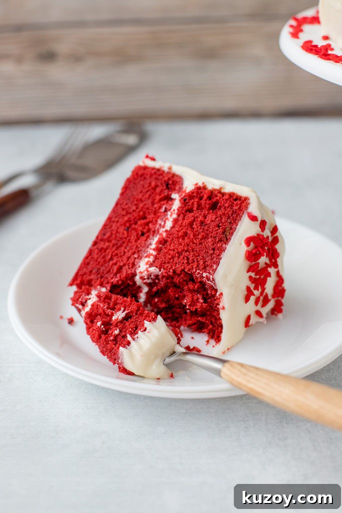 One-Bowl Red Velvet Layer Cake Recipe for Moist Layers 3 A slice of red velvet cake with a generous forkful removed.