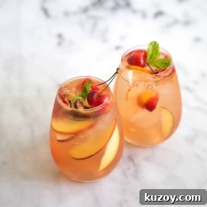 Summer Stone Fruit Sangria Recipe for Bright, Fruity Cocktails 7 two glasses of stone fruit sangria on marble table.