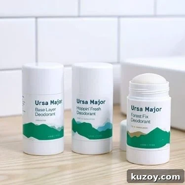 Three sticks of aluminum free deodorant from Ursa Major. They are the Base Layer Deodorant, Hoppin' Fresh, and Forest Fix options. They are on a wooden bathroom counter top.