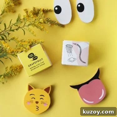 A flatlay of Meow Meow Tweet's grapefruit scented baking soda-free deodorant cream with emjoi cutouts and yellow flowers on a yellow background.