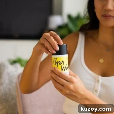 A feminine presenting person with long dark hair holding a Piperwai earth-friendly deodorant stick.