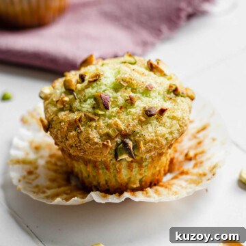 One pistachio muffin with the liner pulled down.