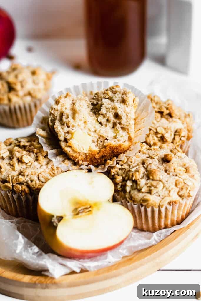Cinnamon Apple Oat Crumble Muffins 10 Tray of apple crumble muffins. One has a bite removed sitting on the top.