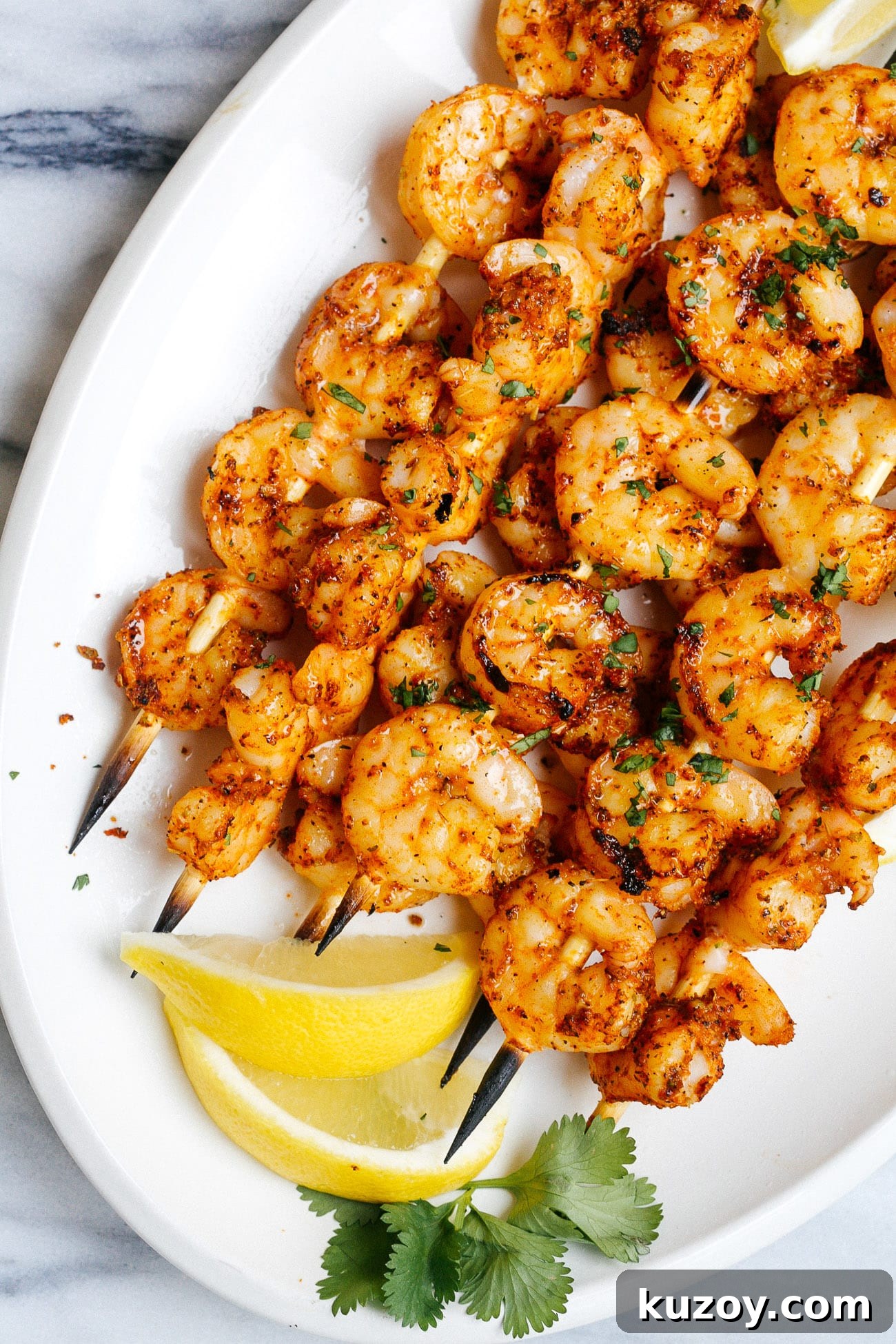 Spicy Cajun Shrimp Skewers with Garlic Butter Dip 6 shrimp kabobs on a white plate