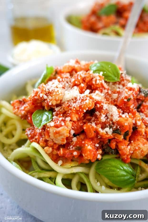 Turkey Bolognese with Zucchini Noodles — Quick Weeknight Dinner 6 Close up on turkey bolognese sauce over zucchini pasta with fresh parmesan on top and a few fresh basil leaves