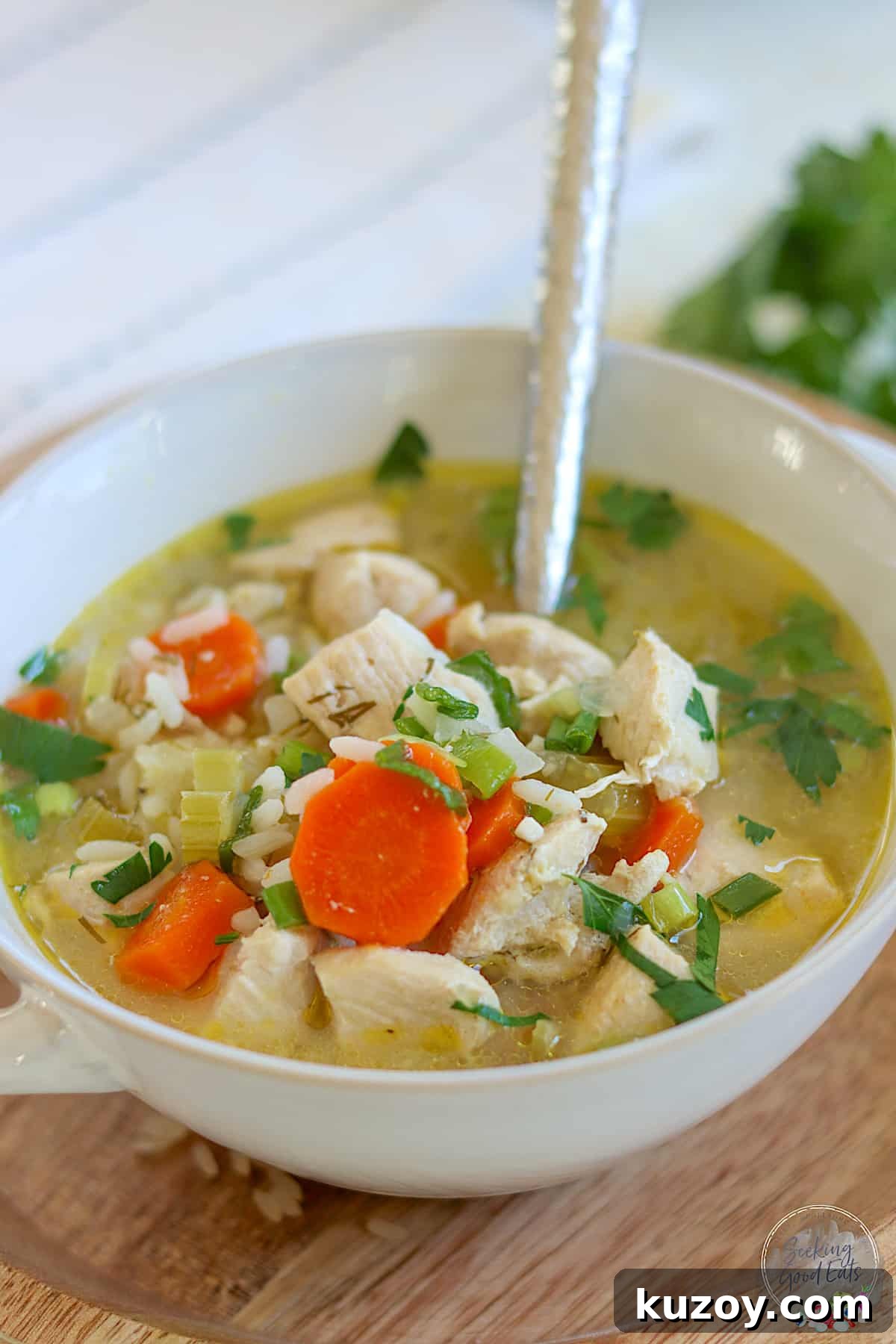 Instant Pot Chicken and Rice Soup Recipe — Comforting Weeknight Meal 2 A white and gray bowl with chicken and rice soup garnished with parsley.