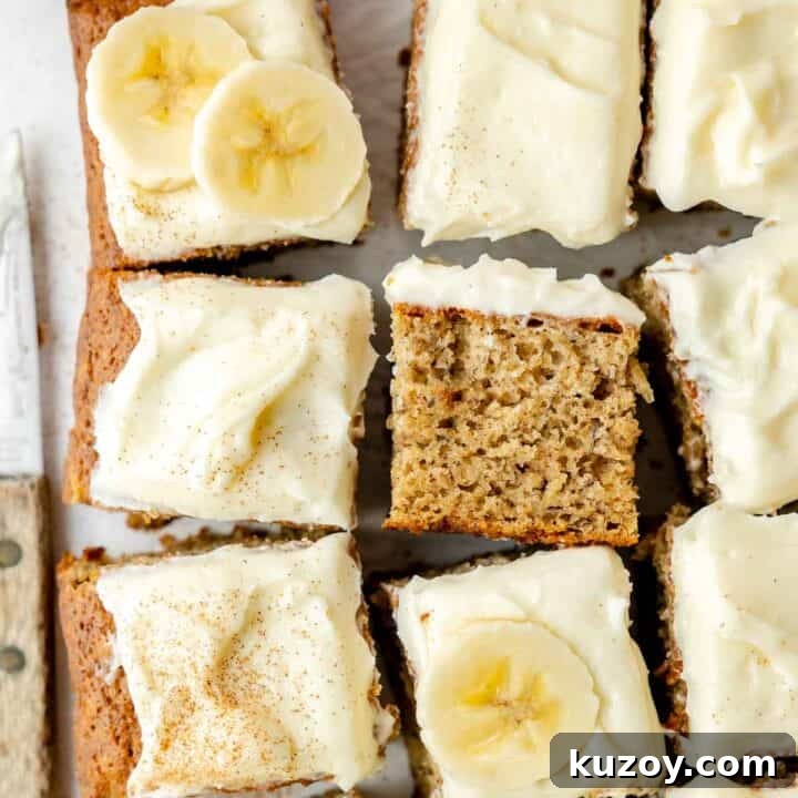 Overhead view of sliced gluten-free banana cake topped with cream cheese frosting, banana slices, and a dusting of cinnamon.