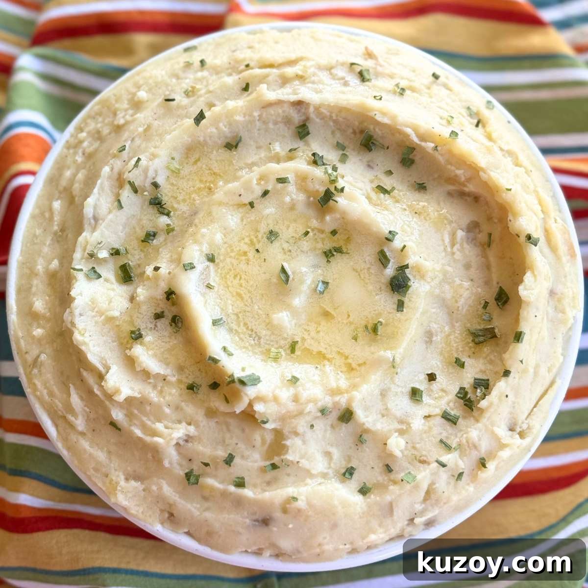 Cream Cheese Crock-Pot Mashed Potatoes — Slow Cooker Recipe 2 Creamy crock-pot mashed potatoes with cream cheese and sour cream in a serving bowl with pools of butter, and chives on top.