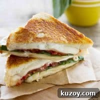 Triple Cheese Grilled Cheese with Fresh Tomato Slices 2 sliced grilled cheese sandwich with tomatoes and basil