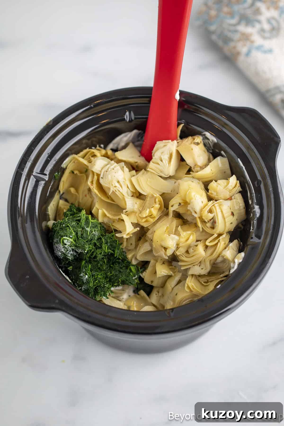Creamy Spinach and Artichoke Dip Recipe for Entertaining 5 Artichoke hearts and spinach in a crock pot.