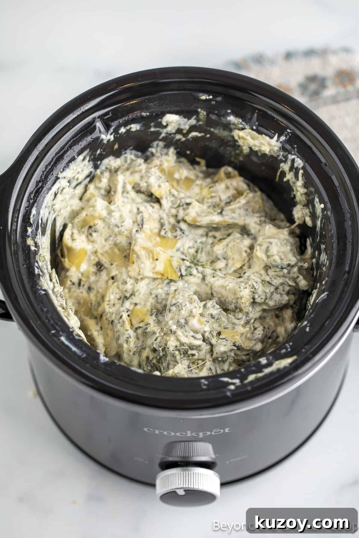 Creamy Spinach and Artichoke Dip Recipe for Entertaining 6 Creamy dip with artichokes and spinach in a crock pot.