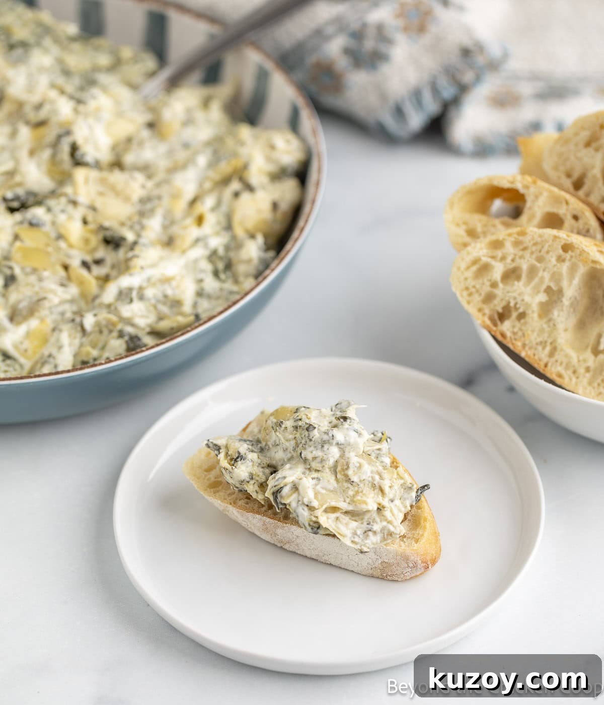 Creamy Spinach and Artichoke Dip Recipe for Entertaining 7 A slice of bread topped with a creamy dip.
