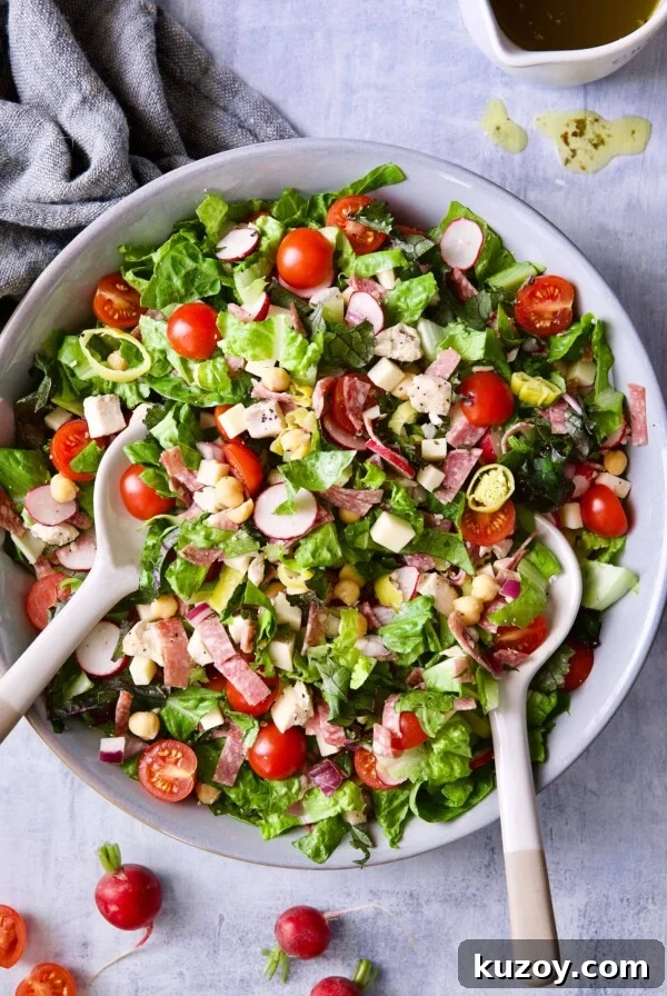 Photo of Italian Chopped Salad with Chicken in gray bowl with serving utensils.