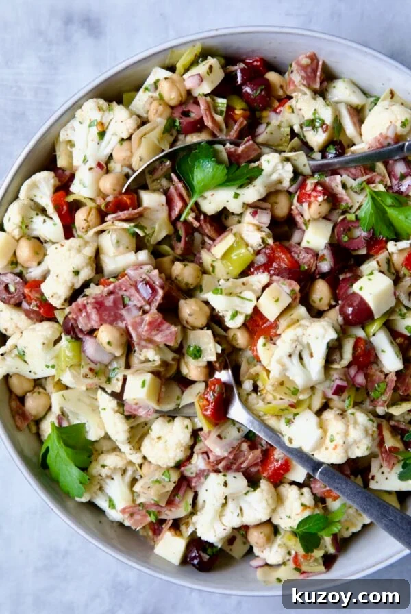 Cauliflower Antipasto Salad in serving bowl with serving utensils.