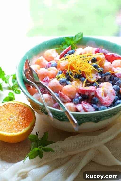 Summer Fruit Salad with Orange Yogurt Vanilla Dressing in green decorative bowl garnished with orange zest.