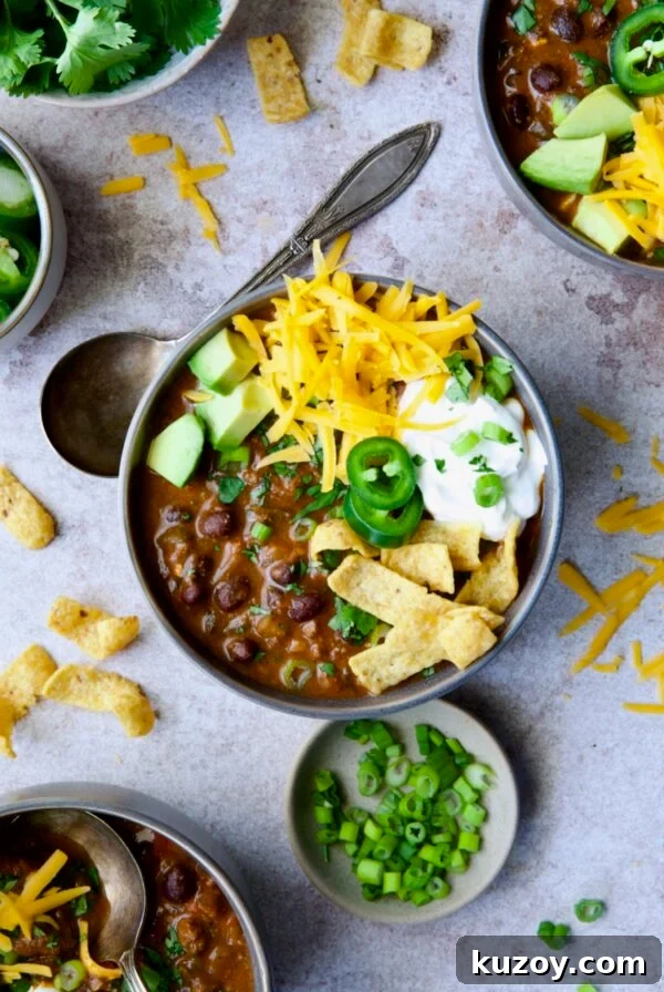 One serving of Beef and Chorizo Chili garnished with avocado, cheddar, sour cream and jalapeno.