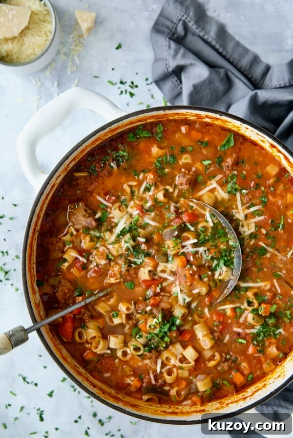 Italian Sausage Soup in white Dutch oven garnished with fresh parsley and Parmesan cheese.
