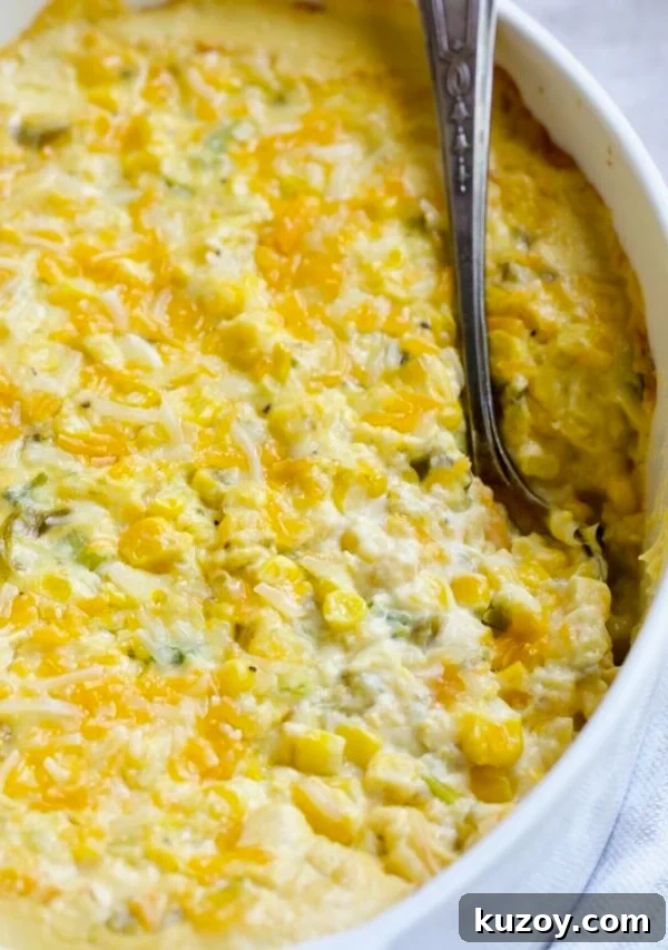 Cream Cheese Corn Casserole with Green Chiles in white oval baking dish with serving spoon.