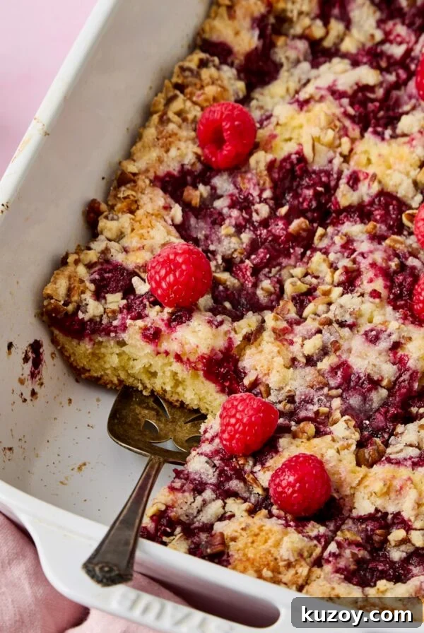 Easy Raspberry Coffee Cake cut into pieces with pie server picking one up.