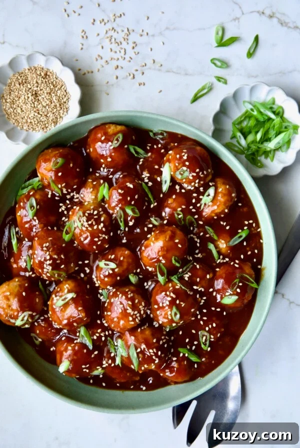 Asian Chicken Meatballs in round green bowl garnished with sesame seeds and scalllions.