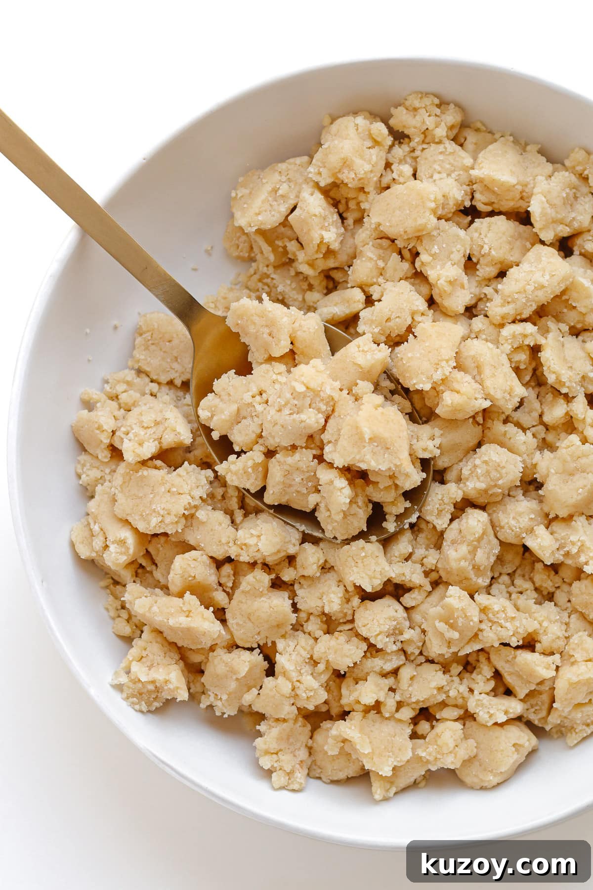 Homemade streusel topping in a white bowl with gold spoon.